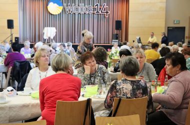 Frauen sitzen an gedeckten Tischen.