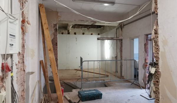 Eine Baustelle in einem Gebäude. Kabel hängen von der Decke.