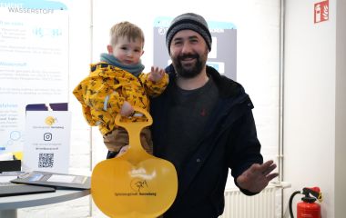 Ein Besucher der Ausstellung trägt ein Kind auf seinem Arm.