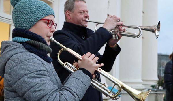Ein Kind und ein Erwachsener stehen auf dem Balkon des Sonneberger Rathauses und spielen Trompete.
