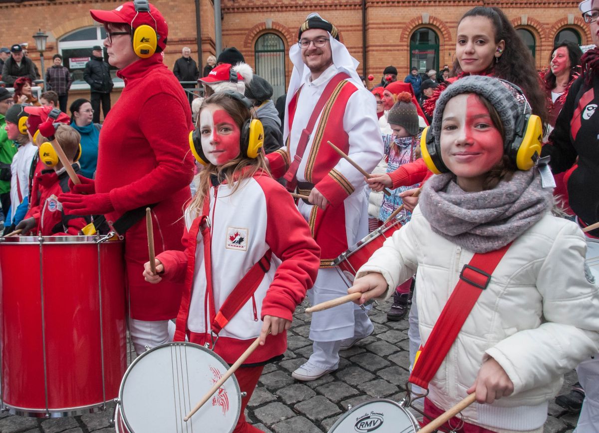 Kostümierte Menschen laufen trommelnd durch die Stadt.