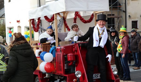 Das Kinder-Prinzenpaar sitzt auf einem Fahrzeug beim Faschingsumzug.