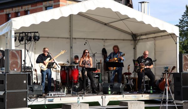 Eine Band tritt auf einer Bühne auf. Es scheint die Sonne.