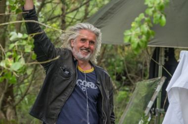 Ein Mann steht im Wald. Der Hintergrund ist unscharf.