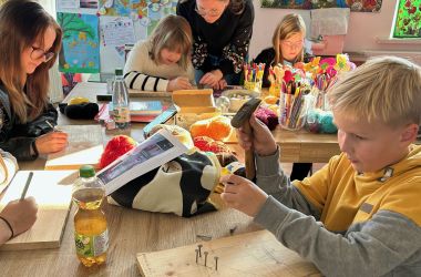 Jungs und Mädchen basteln Nagelbretter.