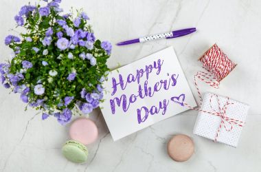 Auf einem Tisch liegen Geschenke und eine Karte mit der Aufschrift: Happy Mothers Day.