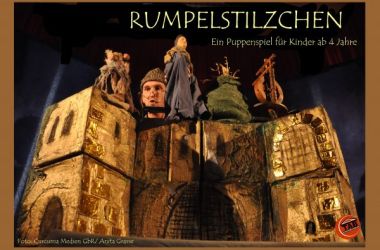 Ein Mann mit Handpuppen hinter einer Burg.