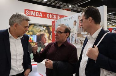 Drei Männer unterhalten sich auf einer Messe.