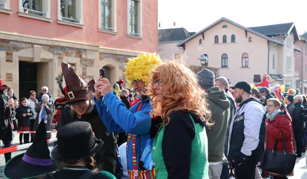 Kostümierte Kinder und Erwachsene stehen an der Straße und beobachten den Umzug.