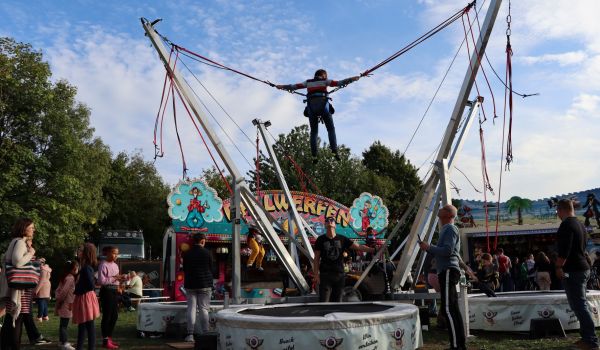 Ein Kind hüpft angegurtet auf einem Trampolin.