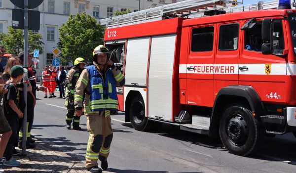 Männer in Feuerwehrkleidung neben einem Feuerwehrauto.