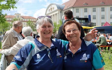 Zwei Helferinnen in blauen Trikots. Im Hintergrund ist das Rathaus der Stadt Sonneberg zu sehen.