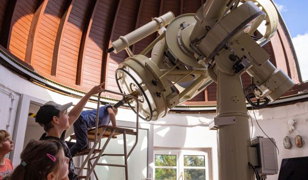 Kinder schauen durch ein Teleksop in der Kuppel.