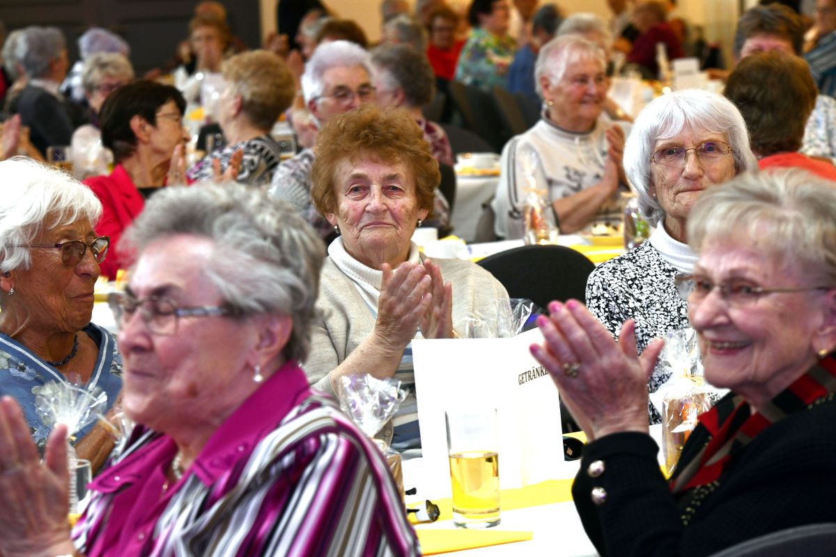 Frauen sitzen an gedeckten Tischen und klatschen in die Hände.