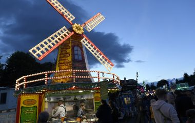 Ein Verkaufsstand mit einer beleuchteten Windmühle darauf. Es ist Dämmerung.