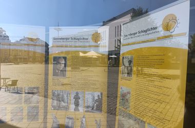 Drei Info-Banner stehen hinter einer Glasscheibe.