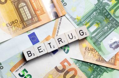 Auf einem Tisch liegen Geldscheine. Drüber steht das Wort Betrug.