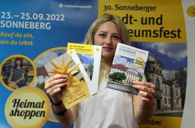 Eine Frau hält verschiedene Broschüren mit der Aufschrift: Stadt- und Museumsfest, in den Händen.