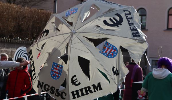 Ein zerschlitzter Sonneneschirm mit der Aufschrift: Rettungsschirm.