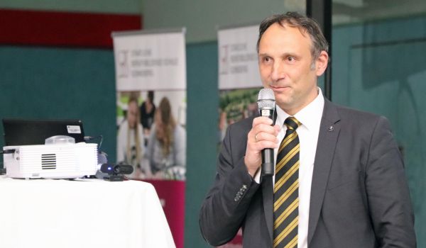 Ein Mann in Anzug spricht in ein Mirkofon.