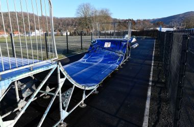 Eine blaue Halfpipe mit Metallgerüst steht neben einem Fußballplatz.