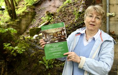 Eine Frau hält ein grünes Buch in den Händen.