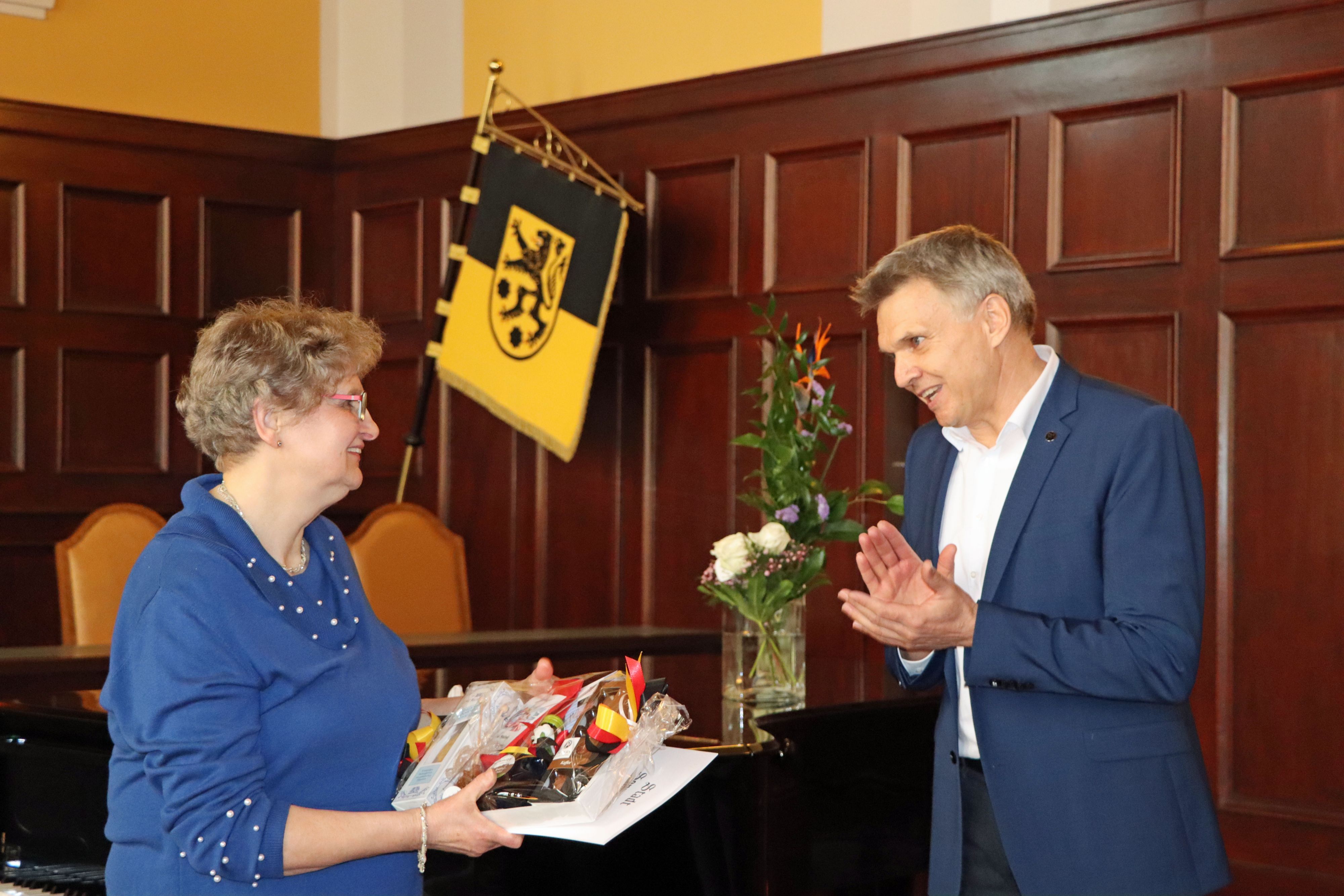 Ein Mann gratuliert einer Frau und überreicht ein Present.