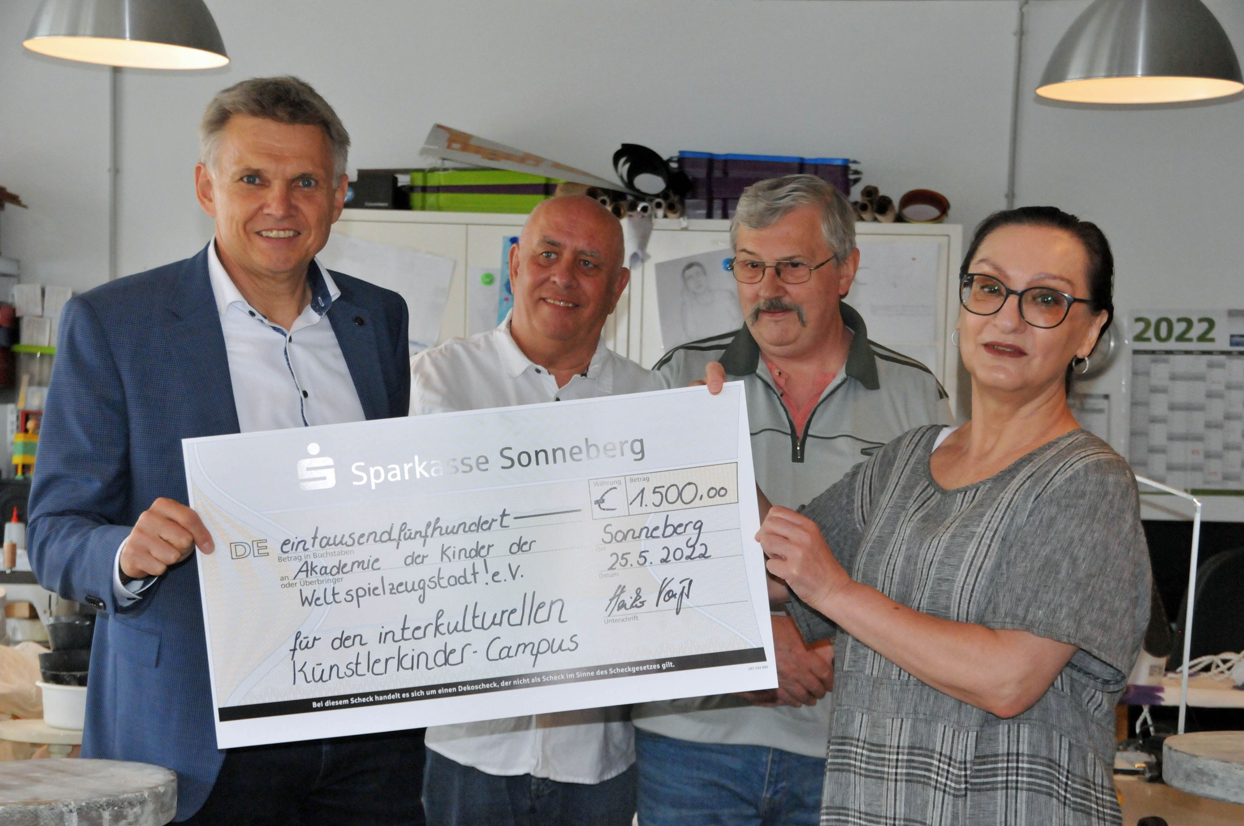 Ein Mann im Anzug überreicht einen Spenden-Scheck.