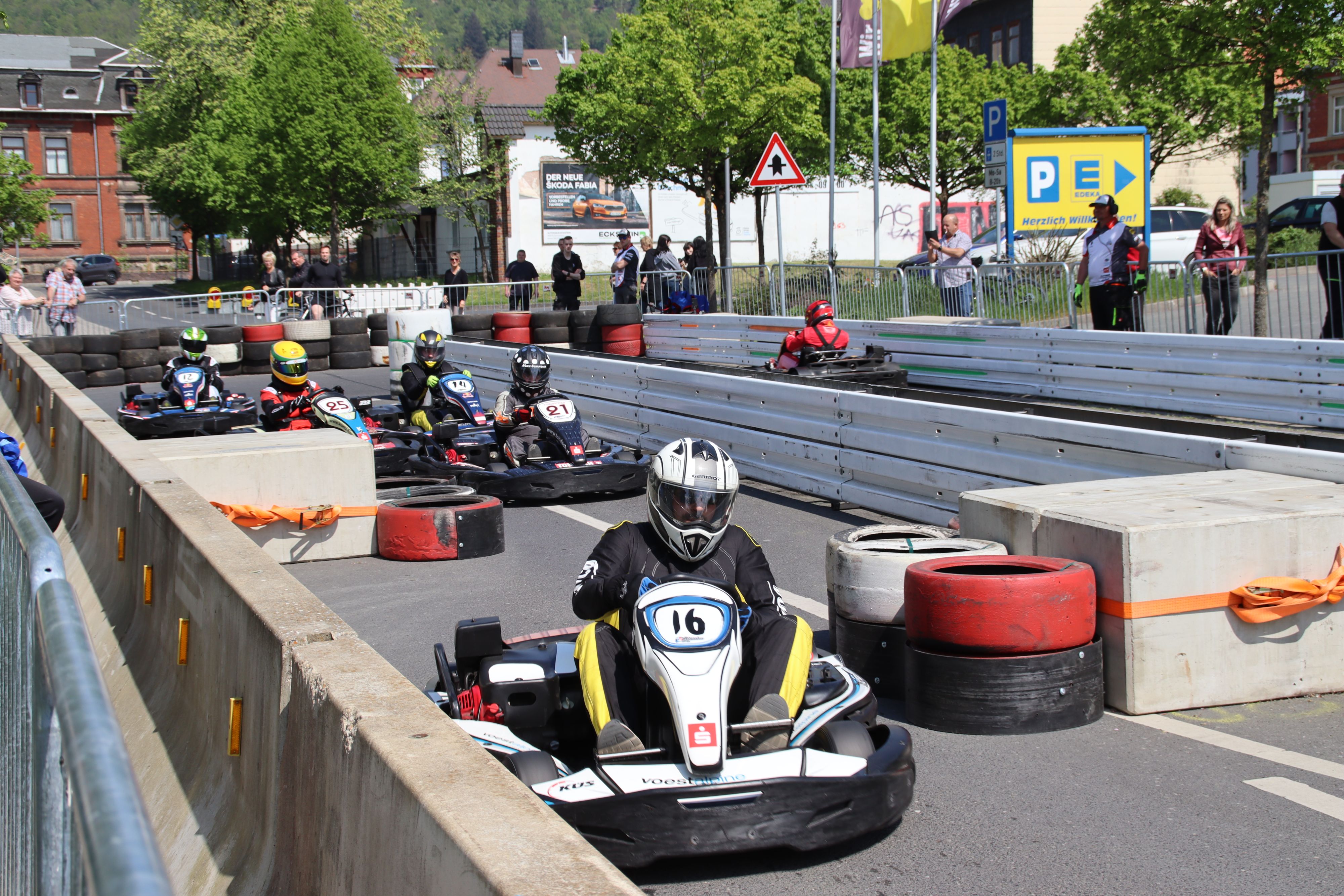 Mehrere Personen fahren in Kartautos über eine Rennstrecke mit Hinternissen.