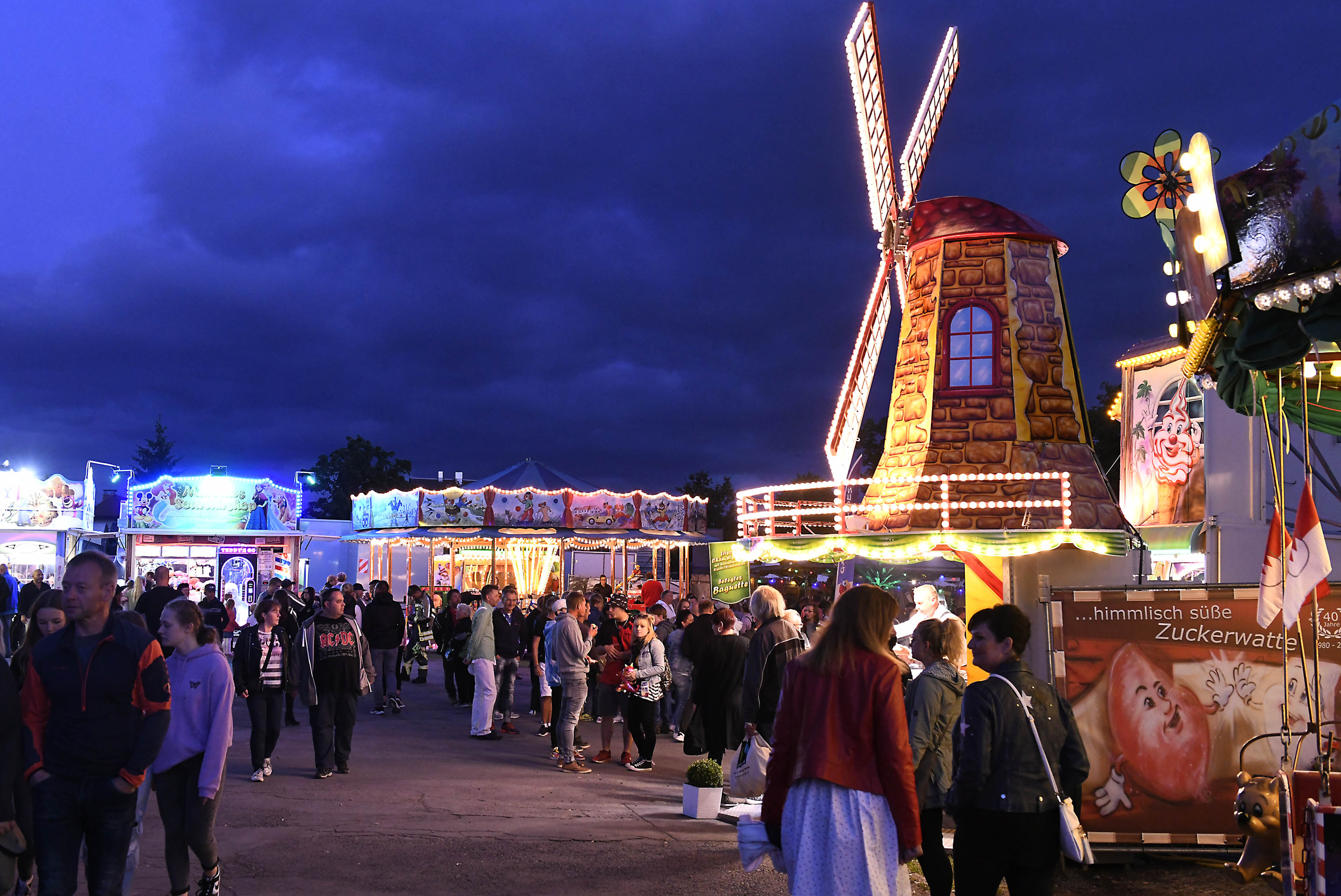 Beleuchtete Fahrgeschäfte und Verkaufsstände bei Nacht.