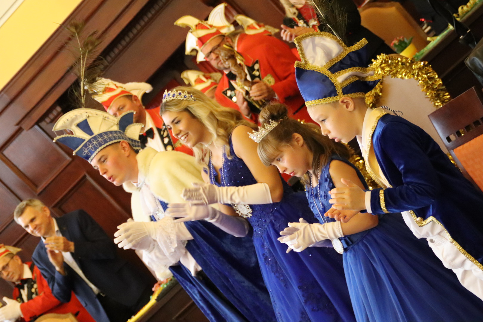 Das Prinzenpaar und das Kinder-Prinzenpaar. Im Hintergrund der Elferrat. Alle klatschen.