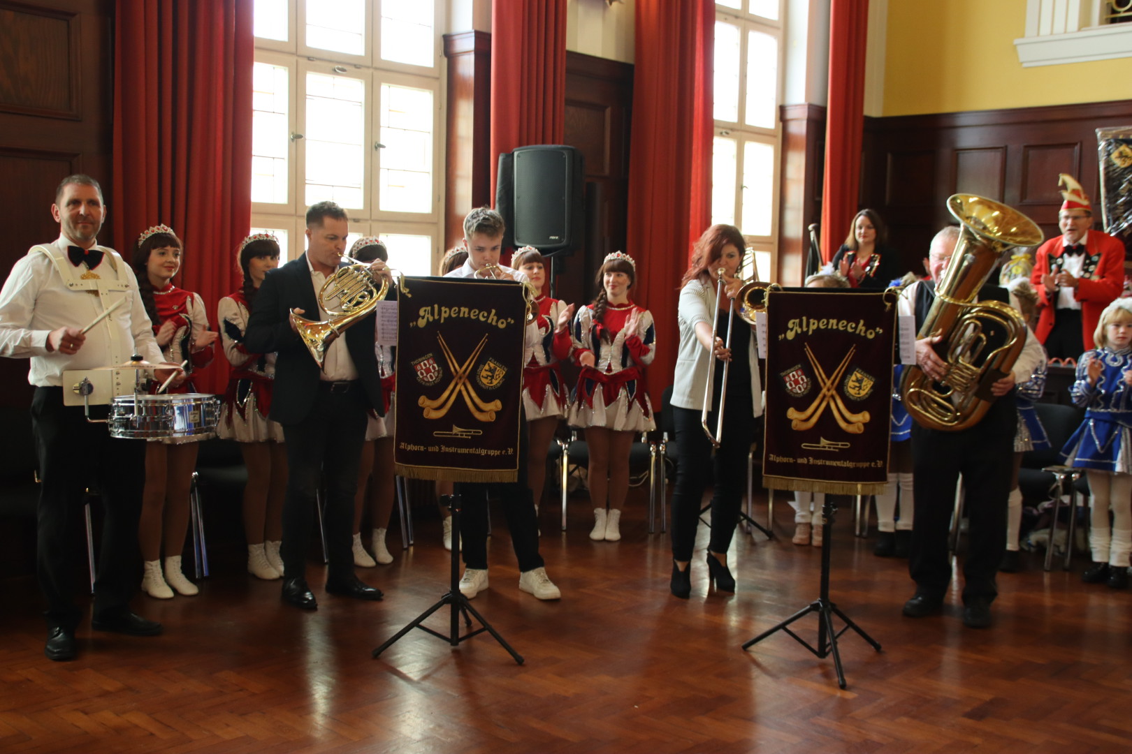 Die Musikkapelle Alpenecho tritt im Rathaussaal auf. Im Hintergrund klatscht der Elferrat und die Tanzmariechen.