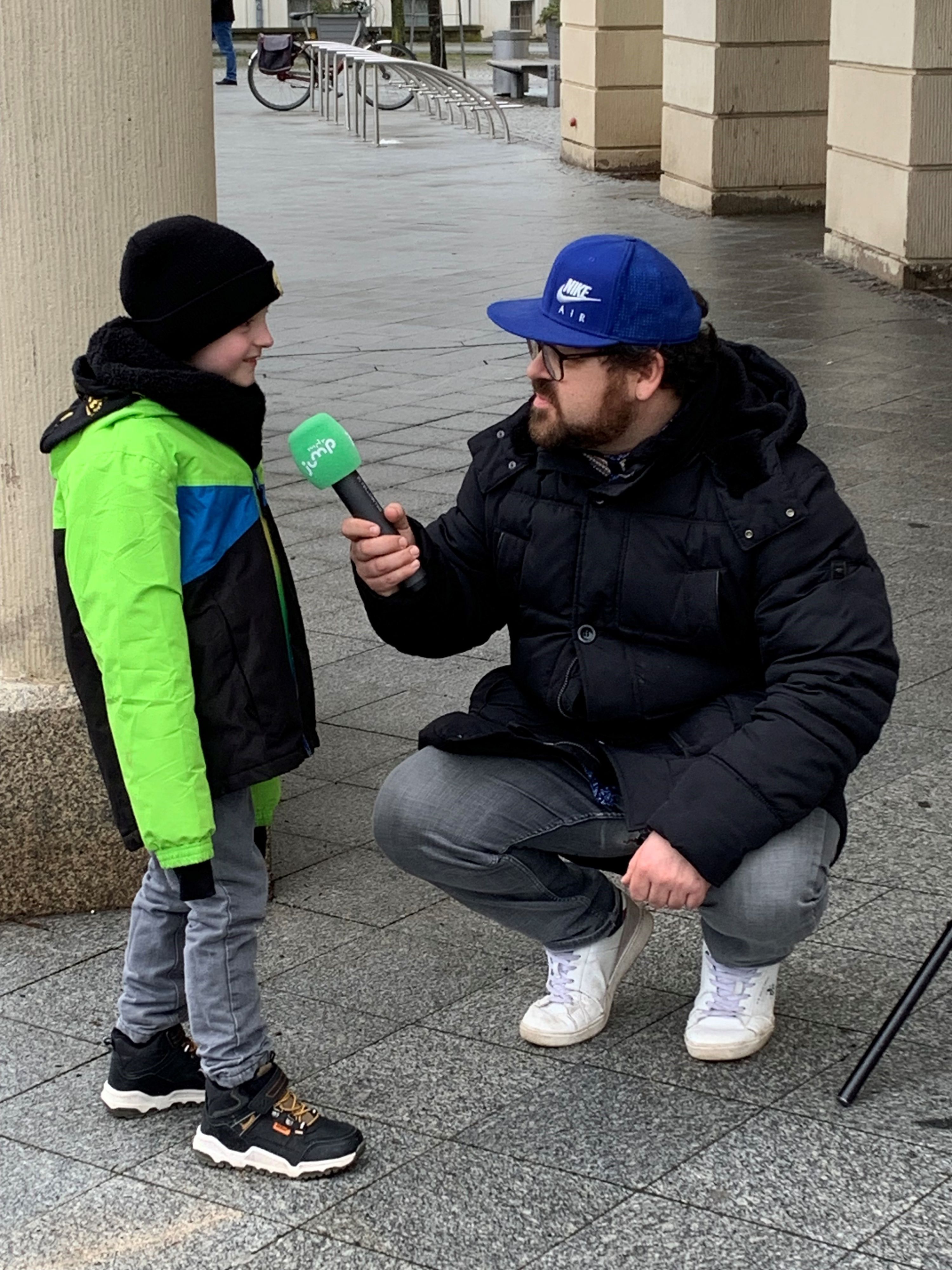 Ein Mann hält einem kleinen Jungen ein Mikrofon hin.