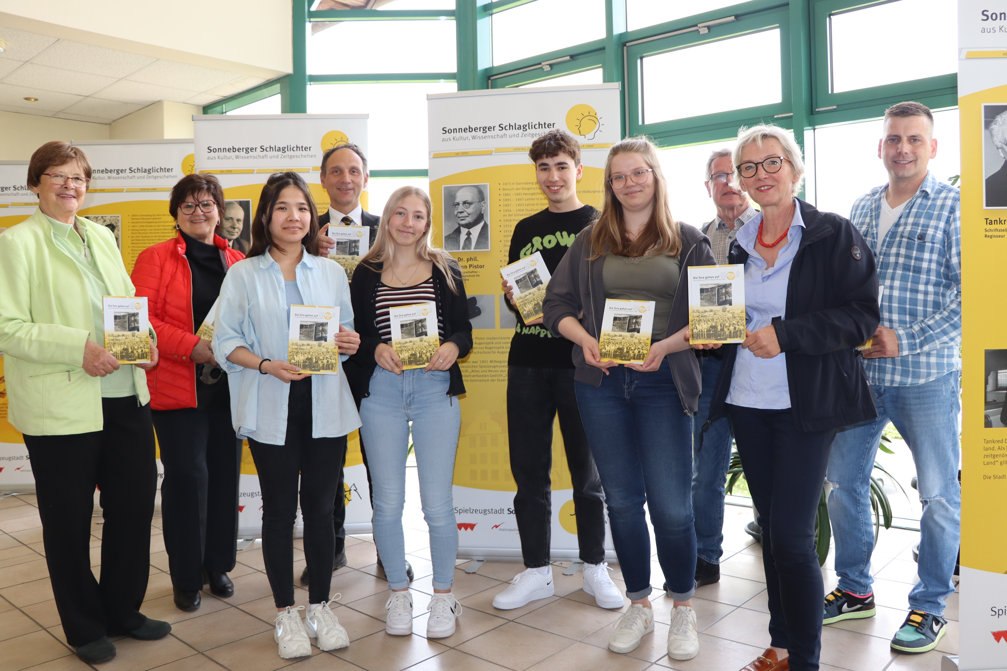 Menschen stehen nebeneinander und halten ein Buch in der Hand.