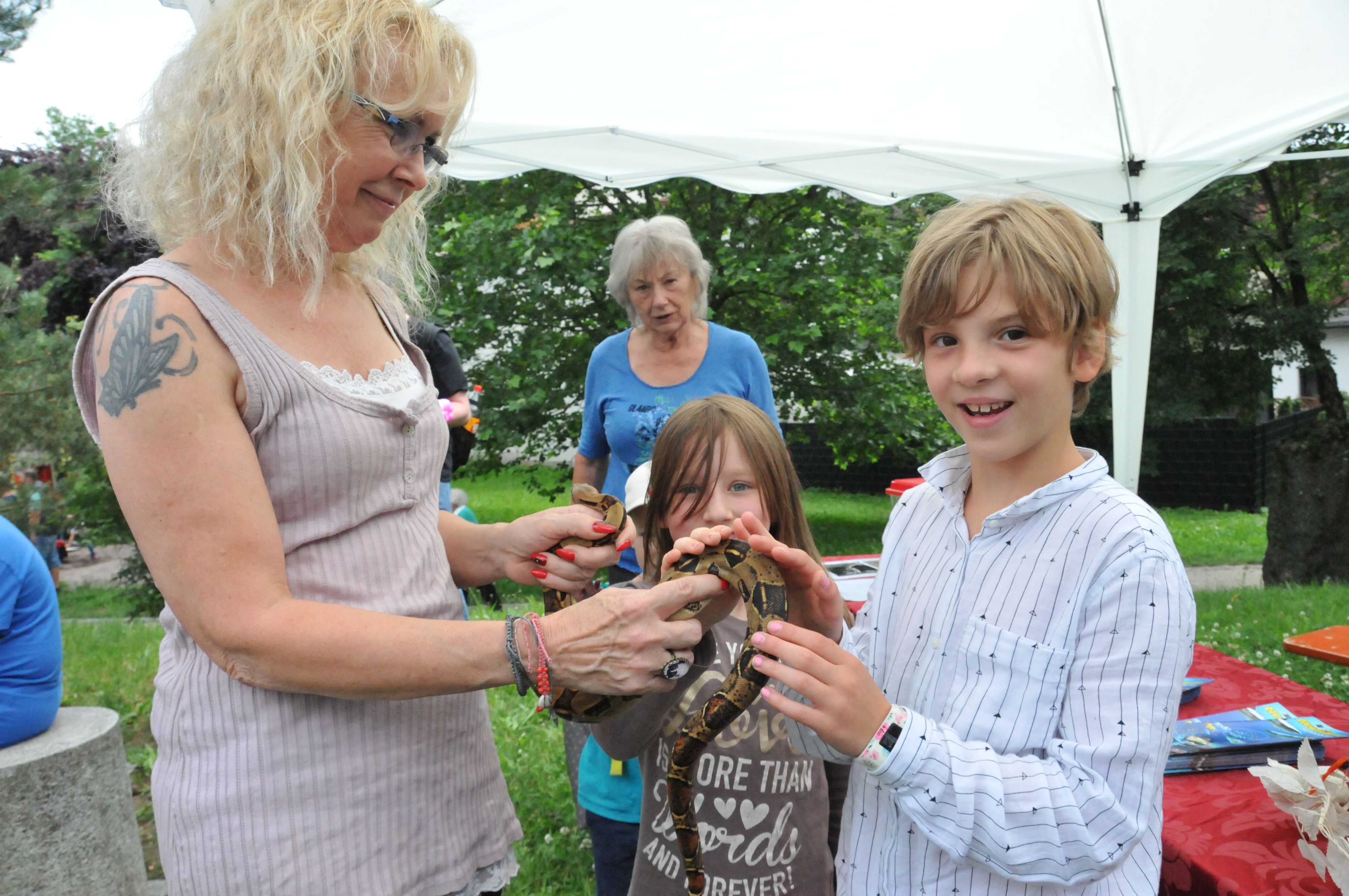 Eine Frau und ein Junge halten eine Schlange in den Händen.