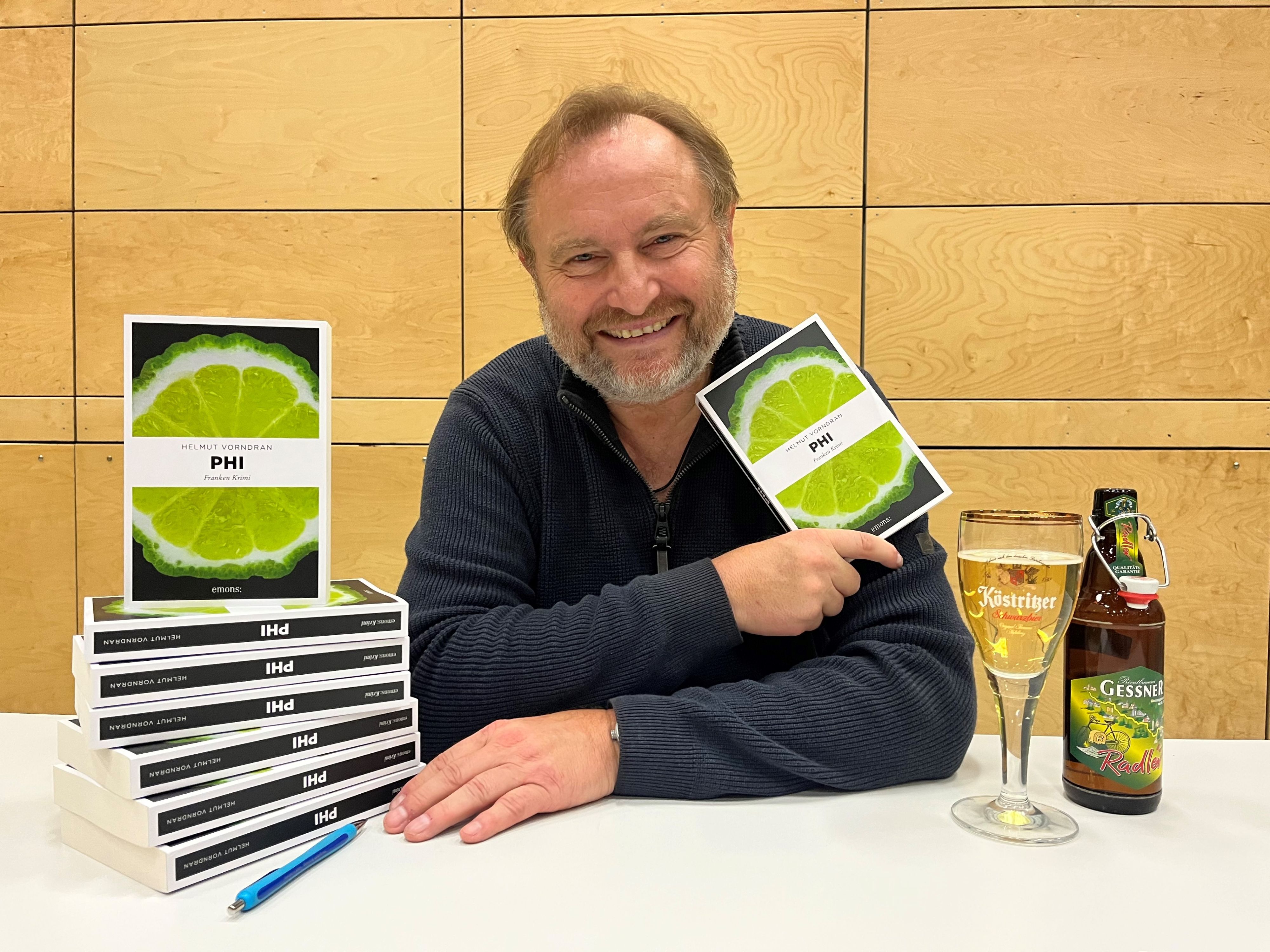 Ein Mann sitzt an einem Tisch und hält ein Buch in der Hand.