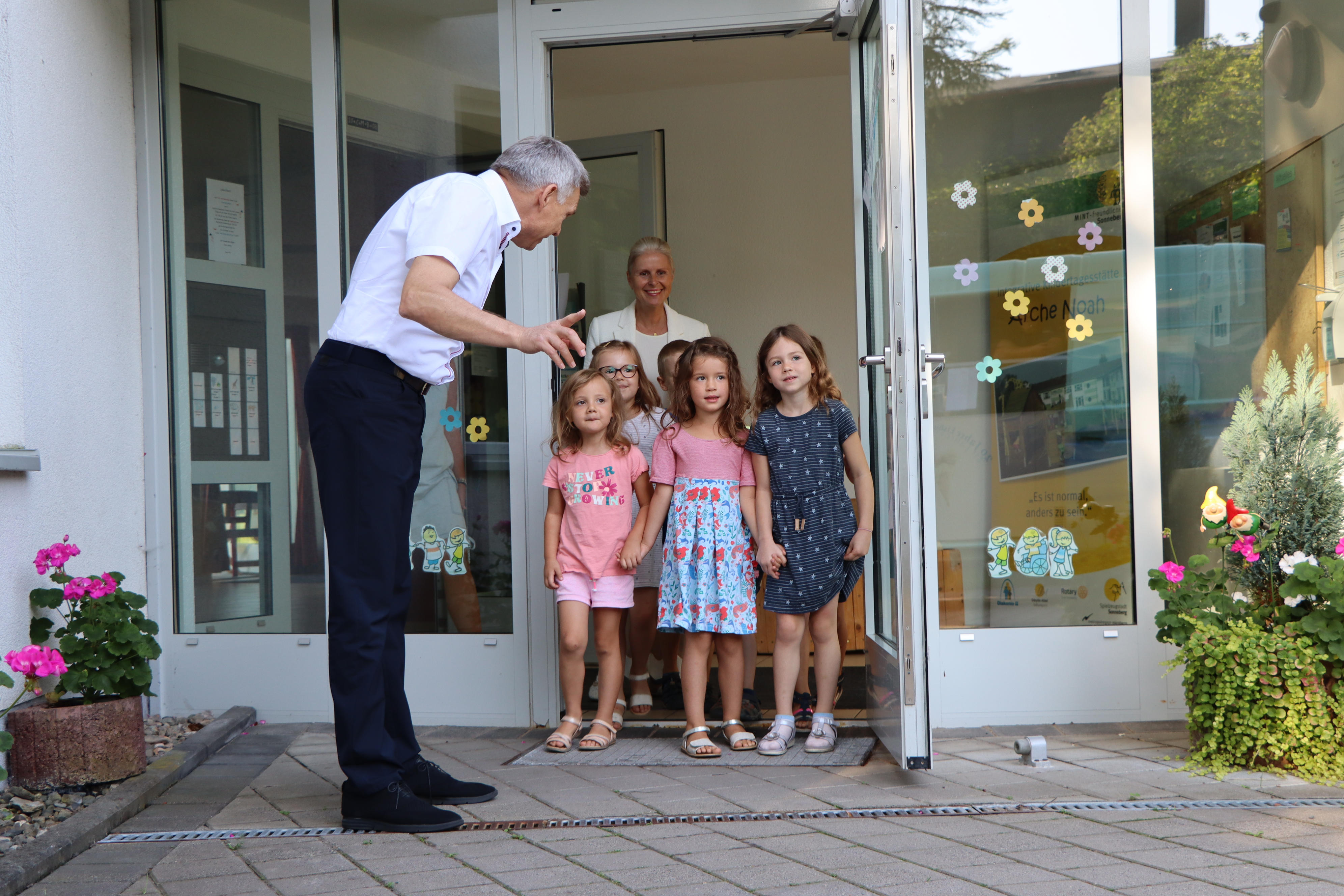 Vor einem Kindergraten stehen Kinder. Daneben steht der Bürgermeister Dr. Heiko Voigt.