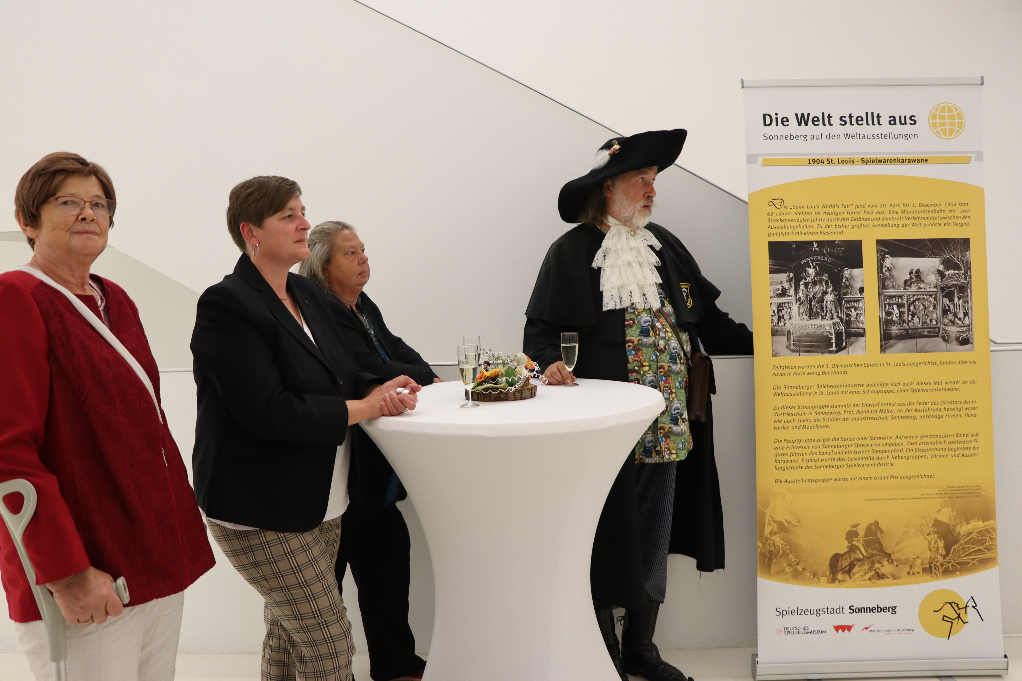 Vier Personen stehen neben einem Geschichtsbanner.