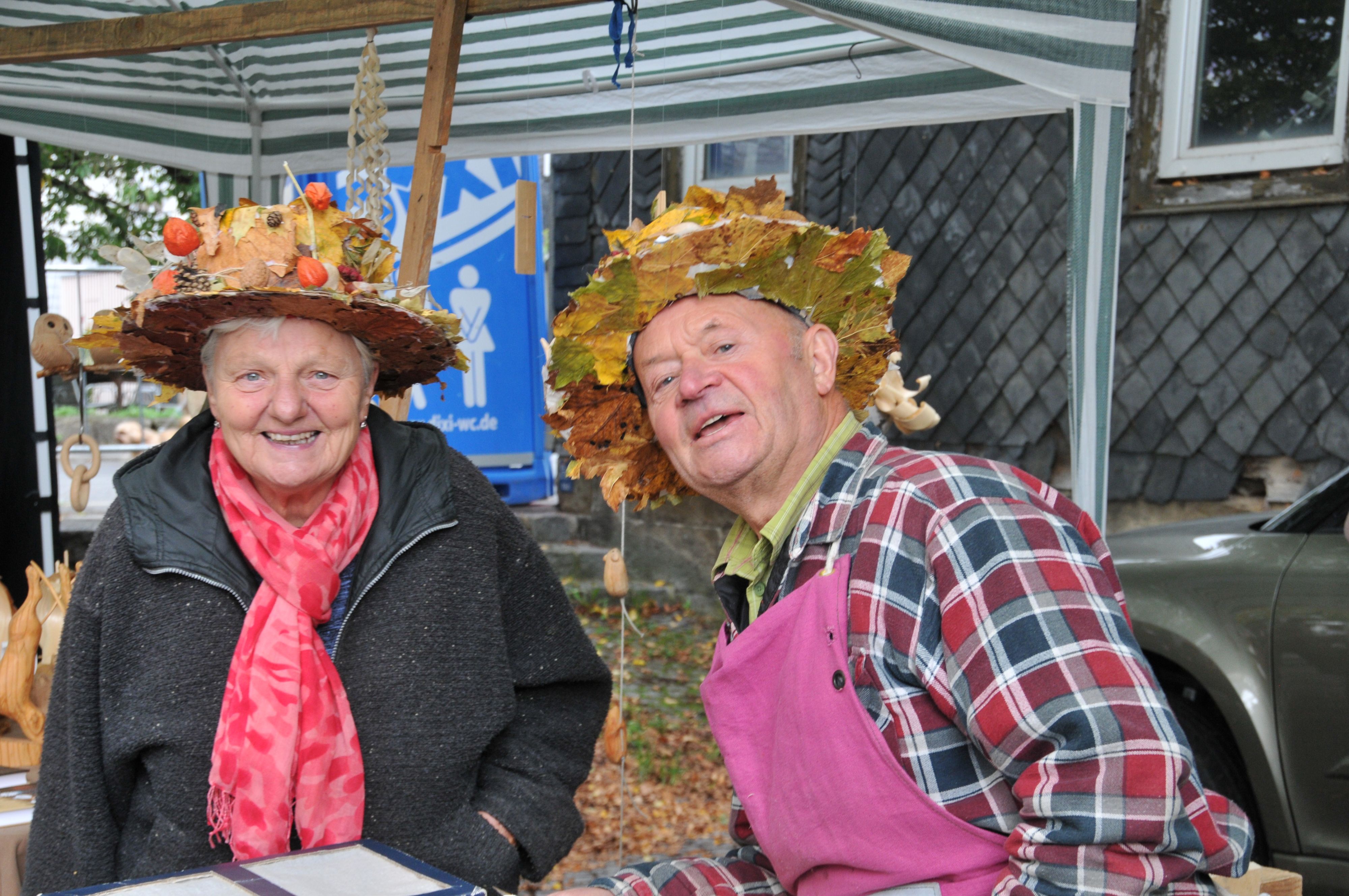Eine Frau und ein Mann tragen einen Hut, der mit Blättern geschmückt ist.