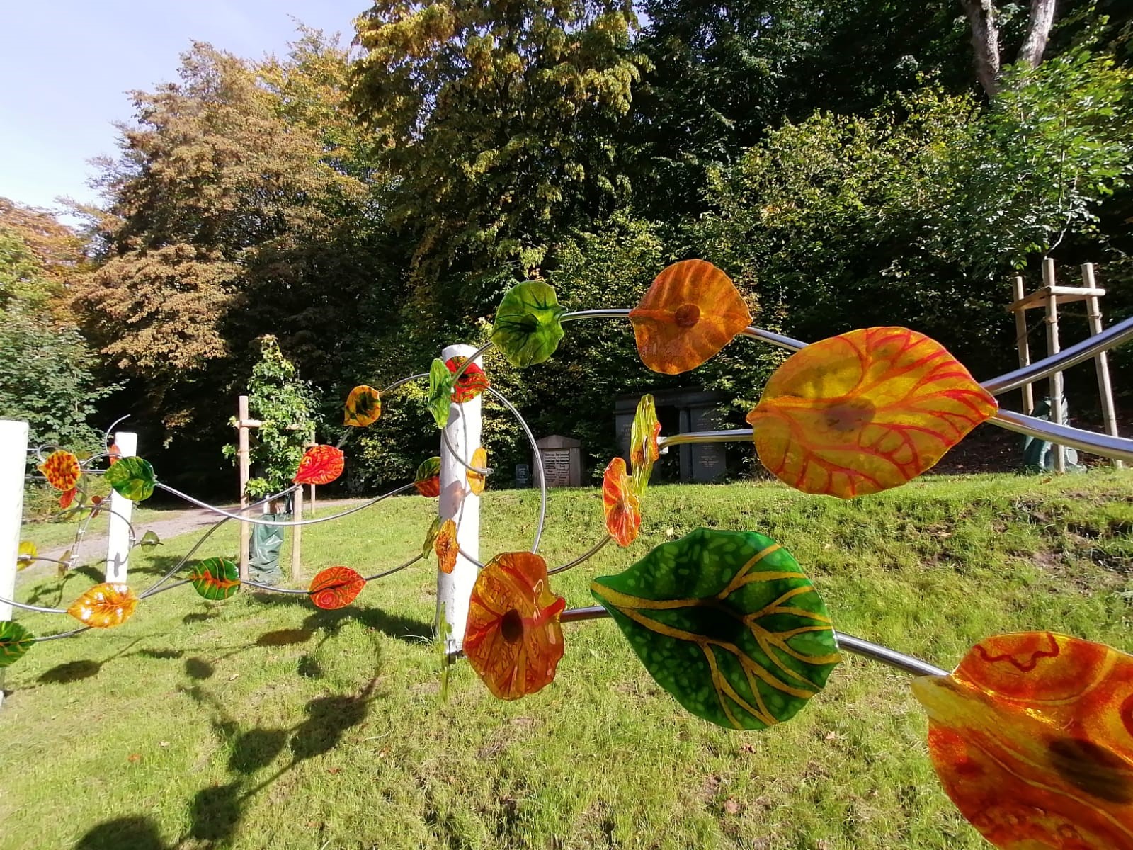 Eine Art Metallzaun mit bunten Blättern daran.