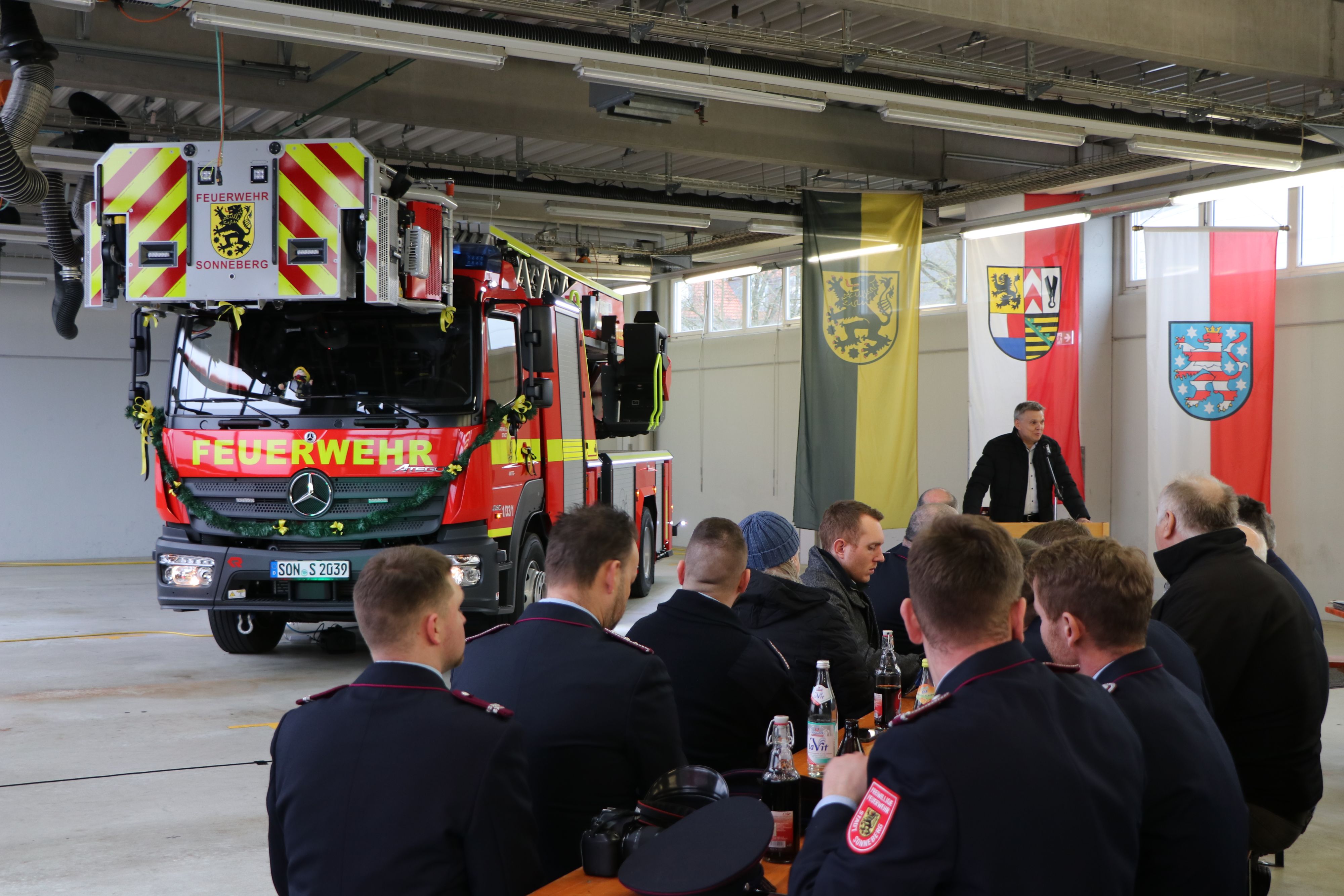 Männer in Feuerwehruniform sitzen vor einem Feuerwehrauto.