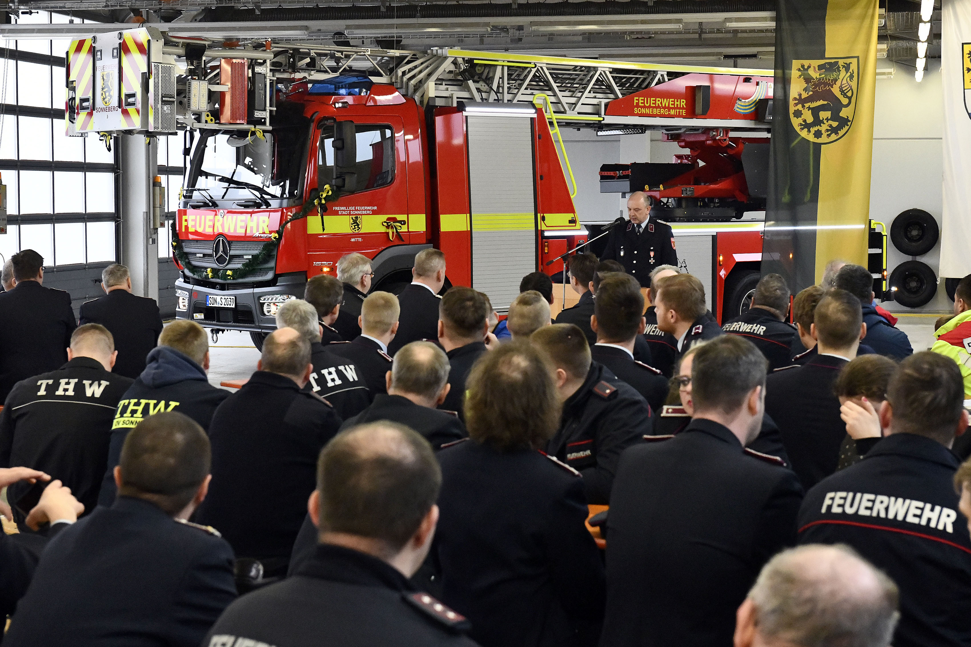 Männer sitzen vor einem Feuerwehrauto.