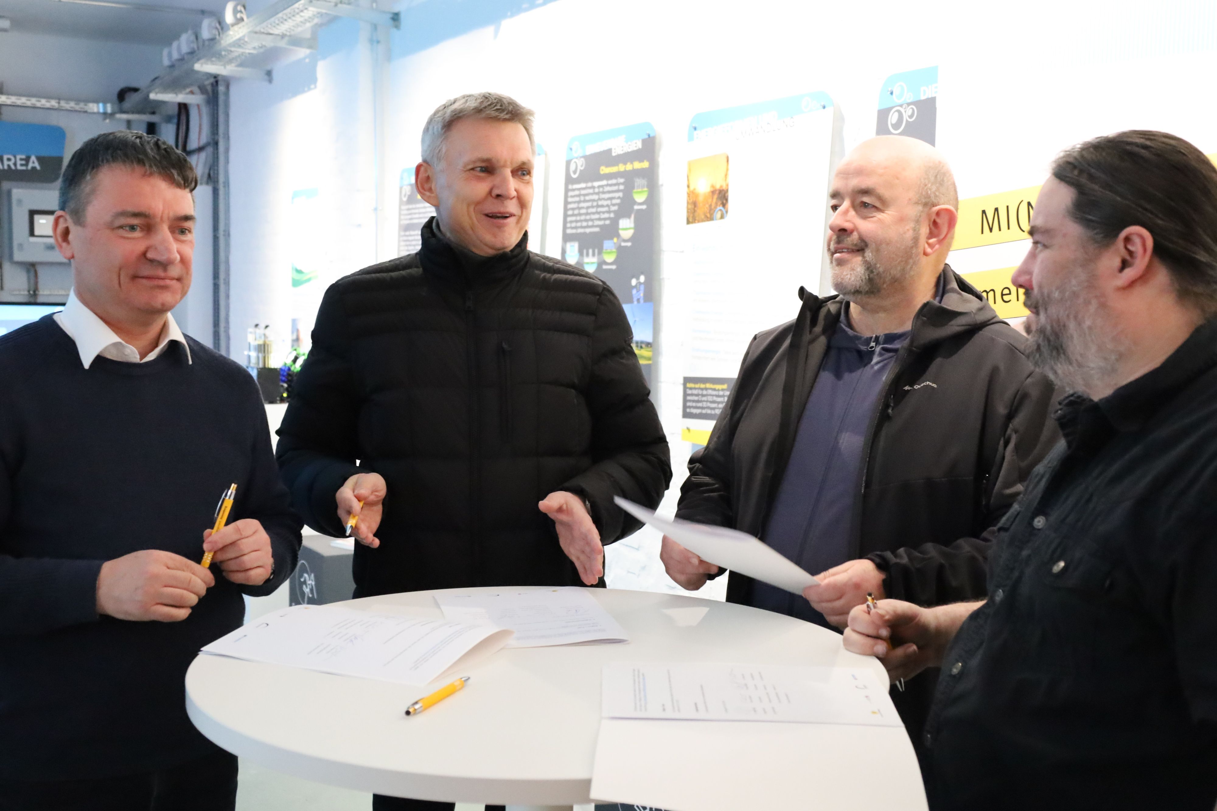 Vier Männer unterhalten sich an einem Stehtisch.