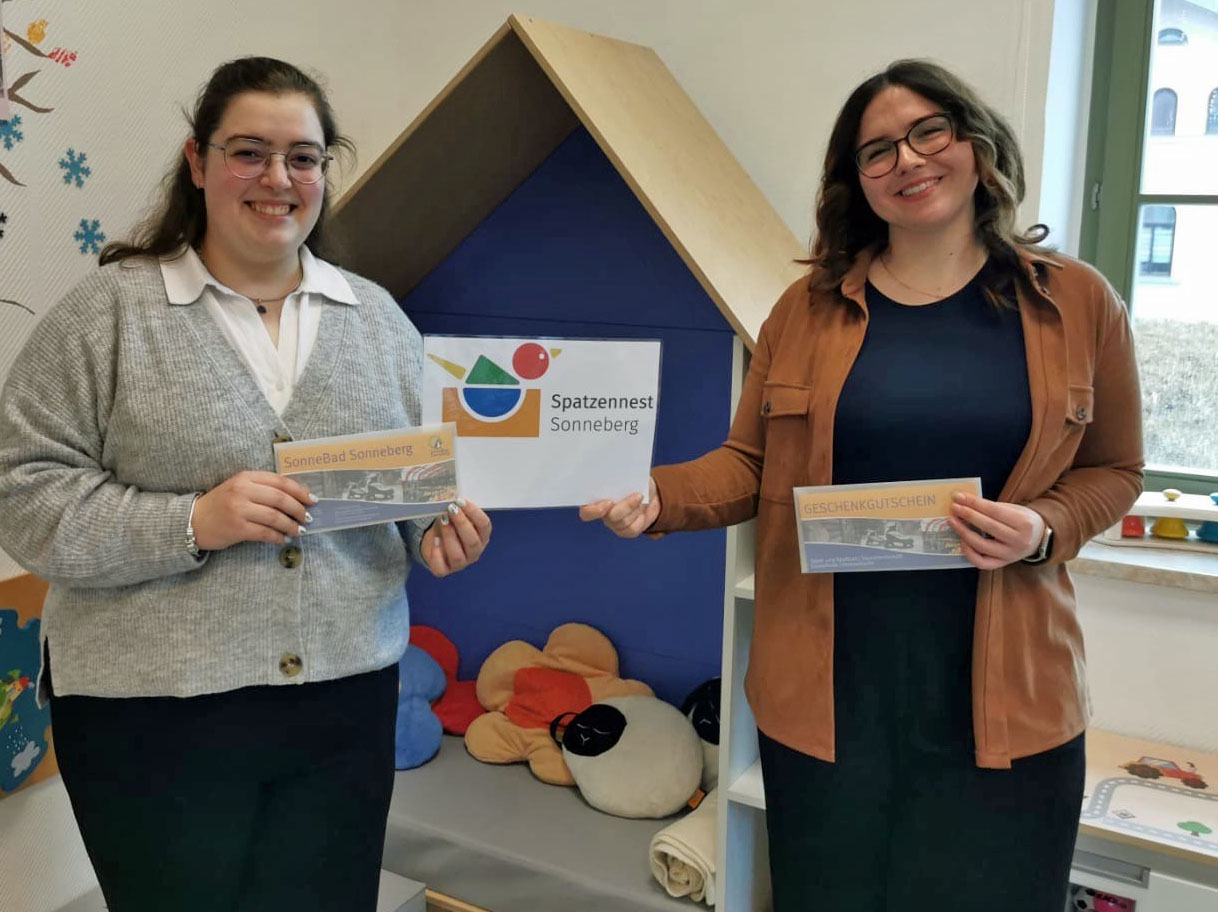 Zwei Frauen stehen nebeneinander und halten einen Zettel mit der Aufschrift Spatzennest Sonneberg in der einen Hand und einen Gutschein fürs Sonnebad in der anderen Hand.
