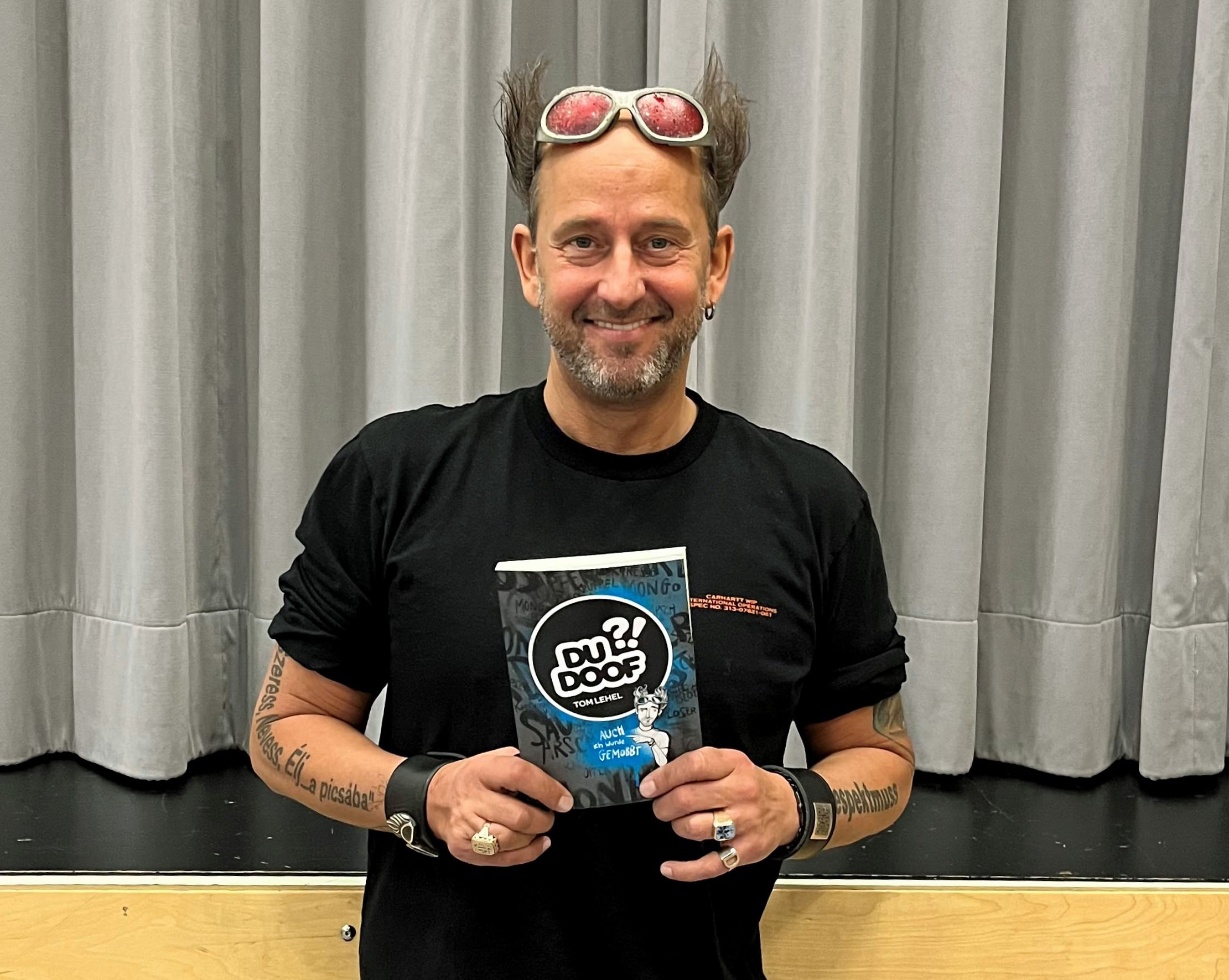 Ein Mann mit einem Buch steht vor einer Bühne.