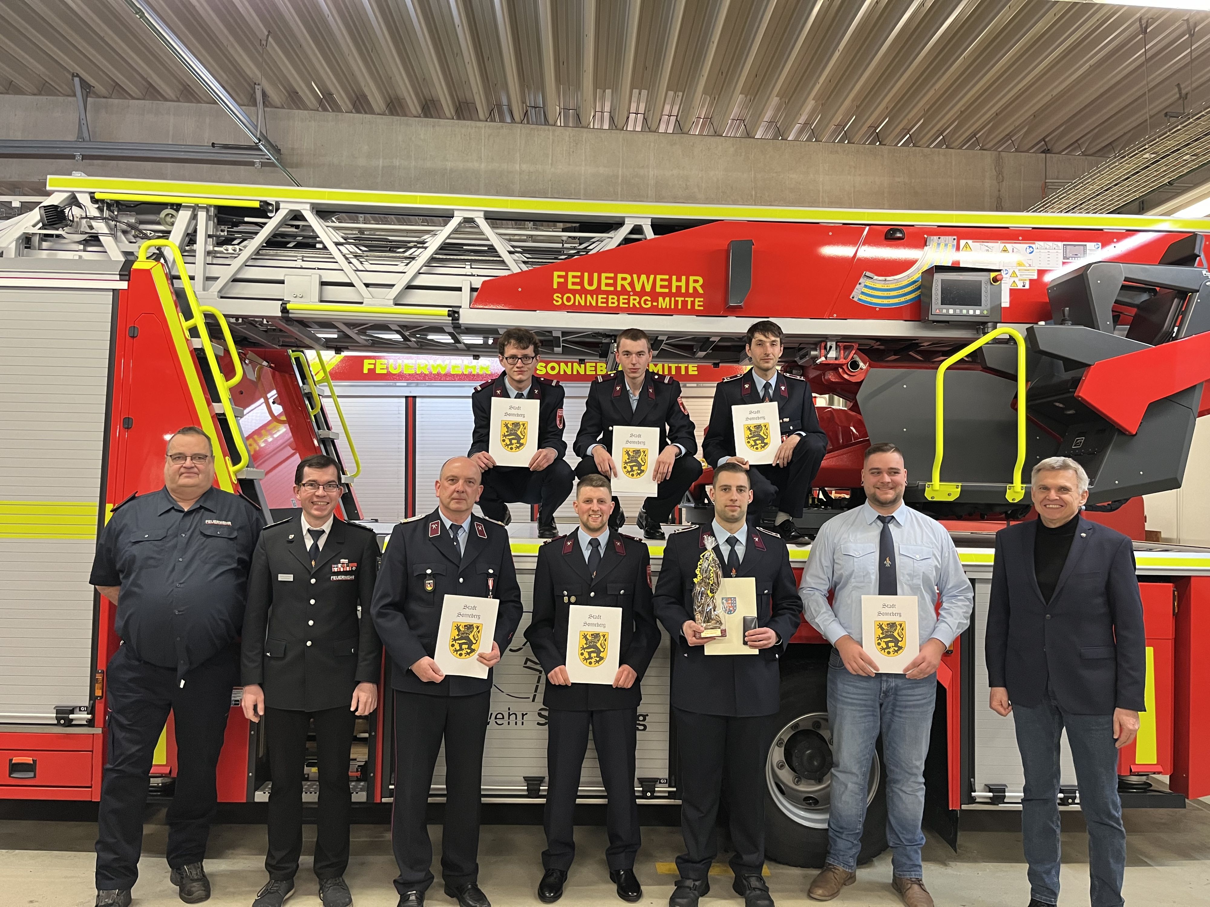 Feuerwehrkameraden stehen vor einem Drehleiterauto.