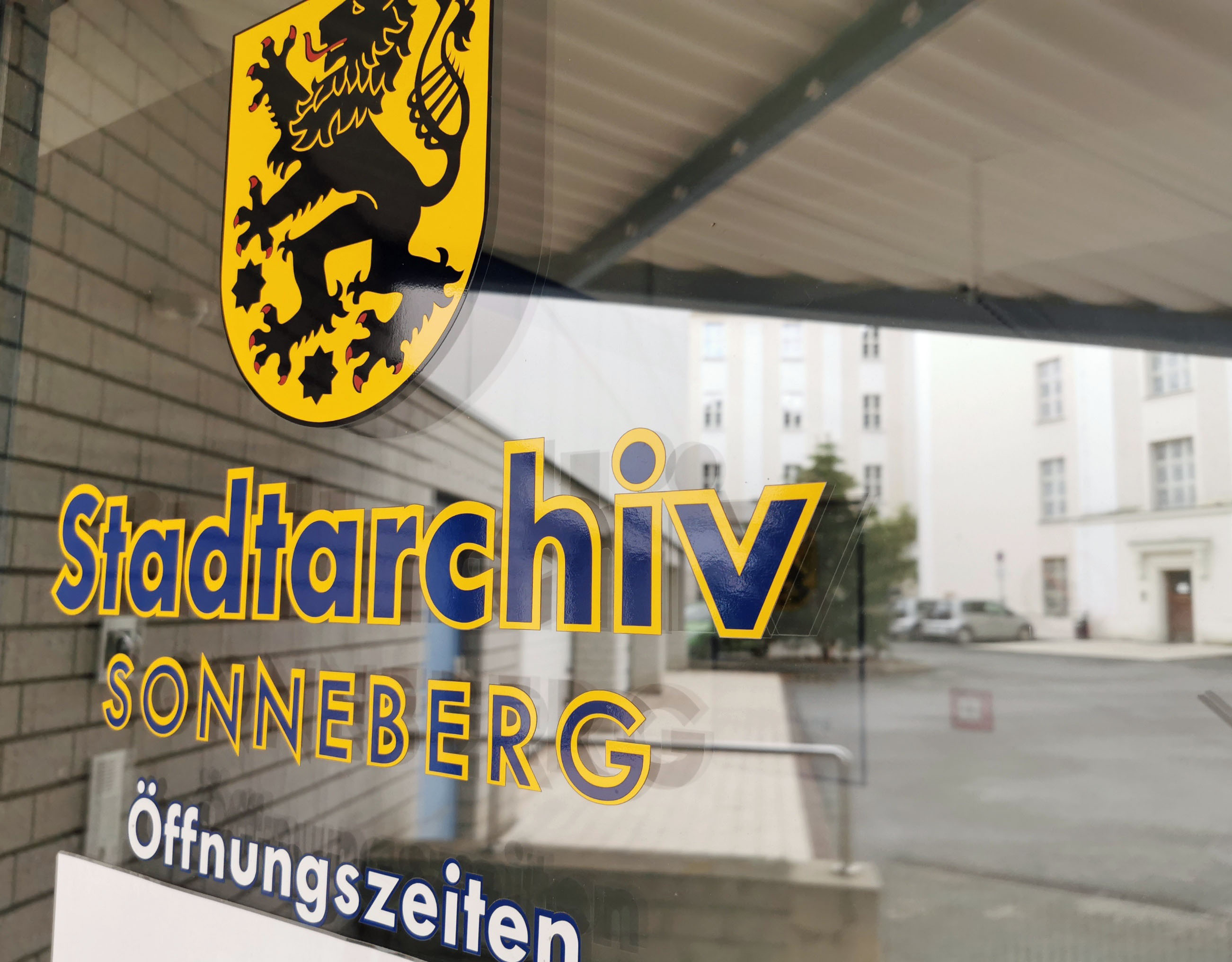 Eine Fensterscheibe mit der Aufschrift Stadtarchiv Sonneberg und Öffnungszeiten.