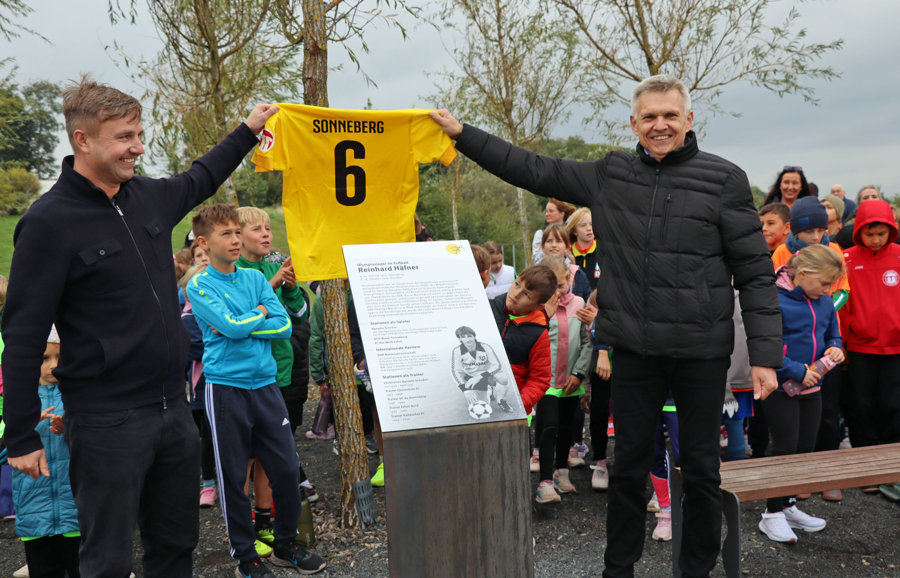 Zwei Männer halten ein gelbes Fußballtrikot mit der Nummer 6 und dem Schriftzug Sonneberg in die Höhe.