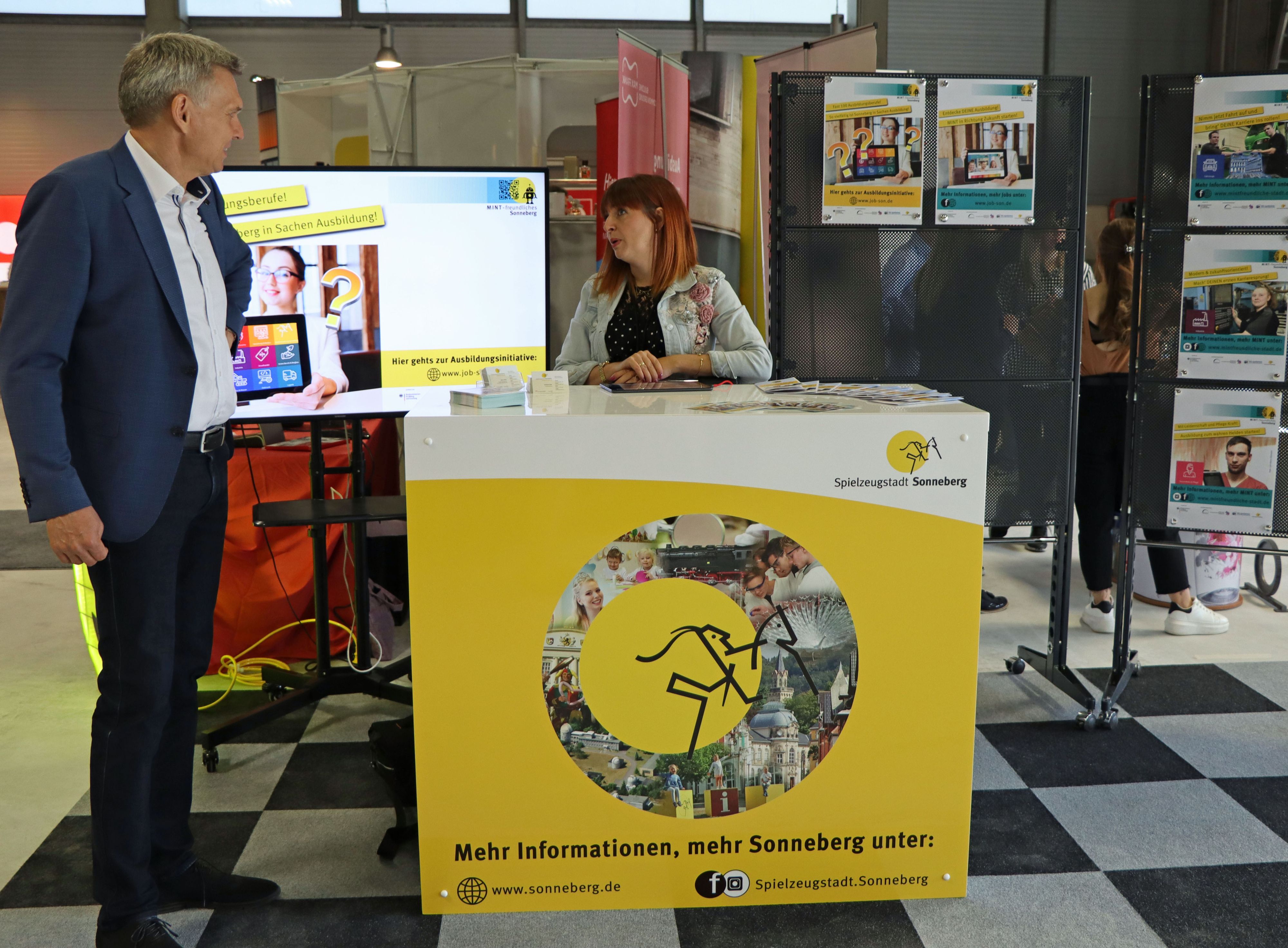 Ein Mann und eine Frau stehen an einem Messestand der Stadt Sonneberg.