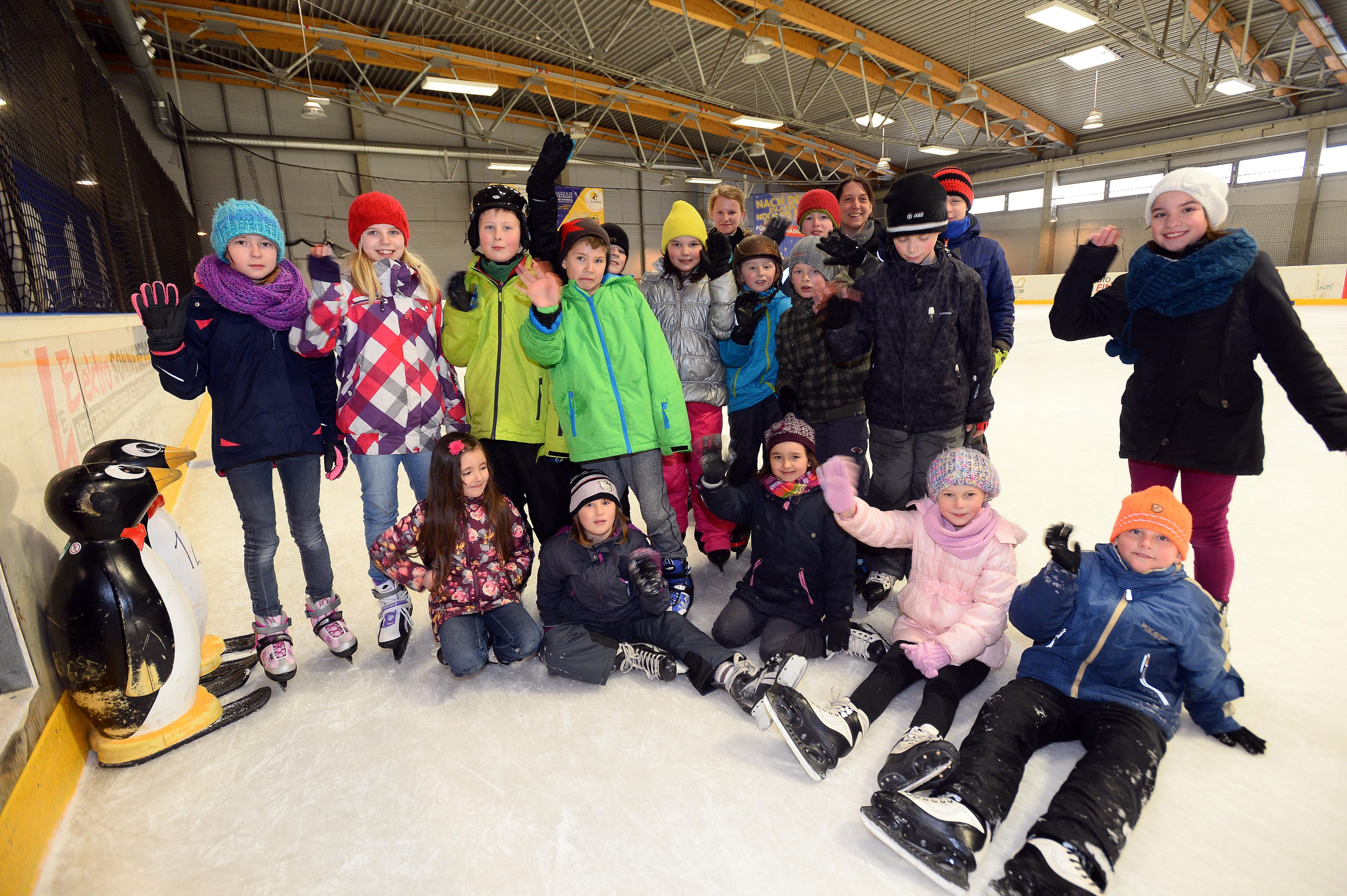 Kinder beim schlittschuhfahren in einer Eishalle.